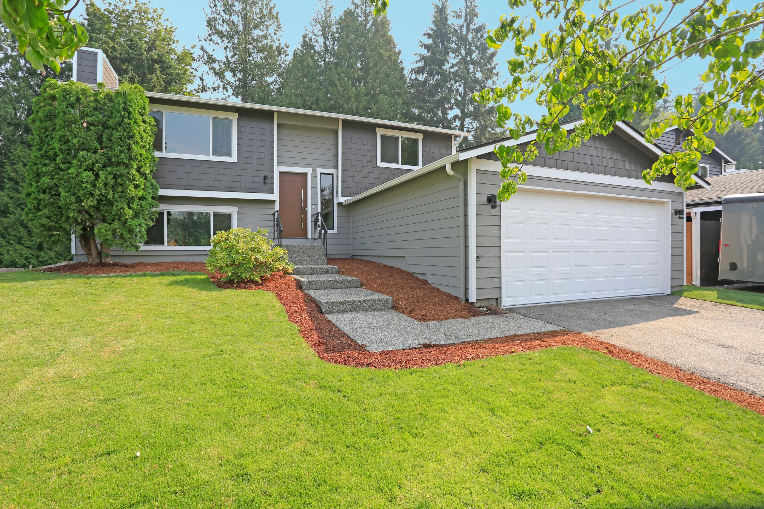 house with grey siding and attached garage with path leading to door