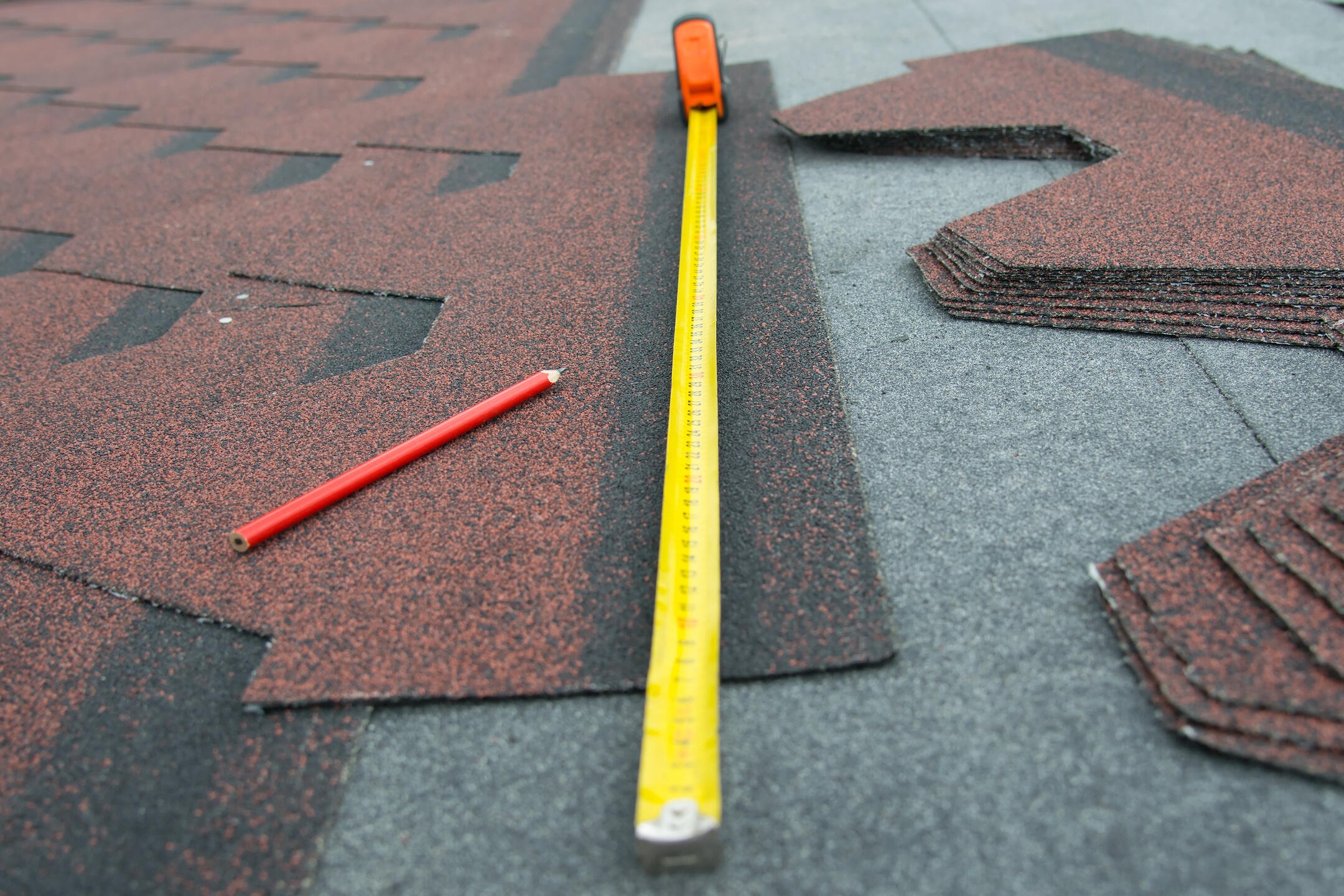 how to measure a roof for shingles-close up of tape measure, pencil, and shingles for roofing