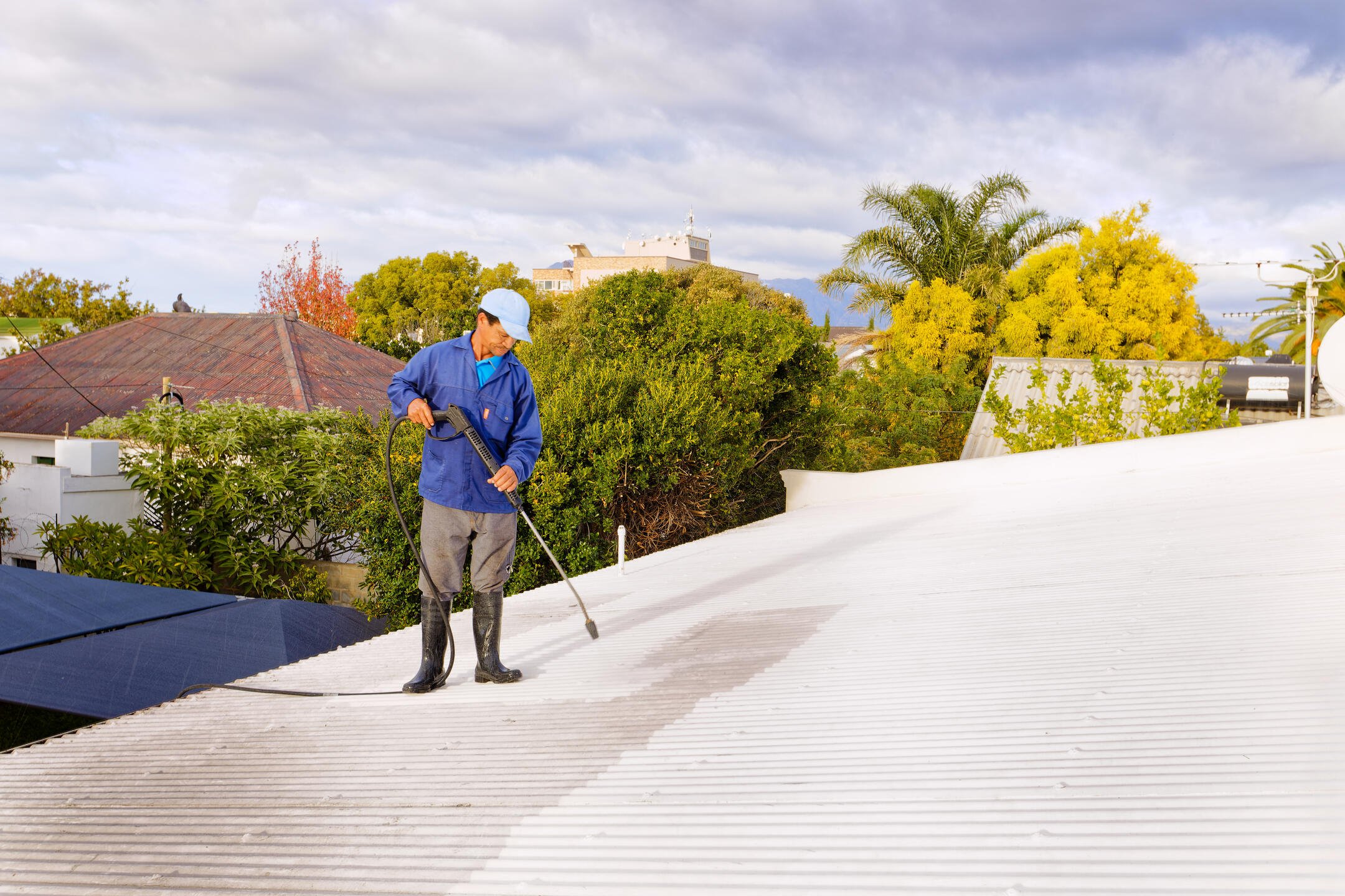 roof coating-man spraying white coating on a sloped roof