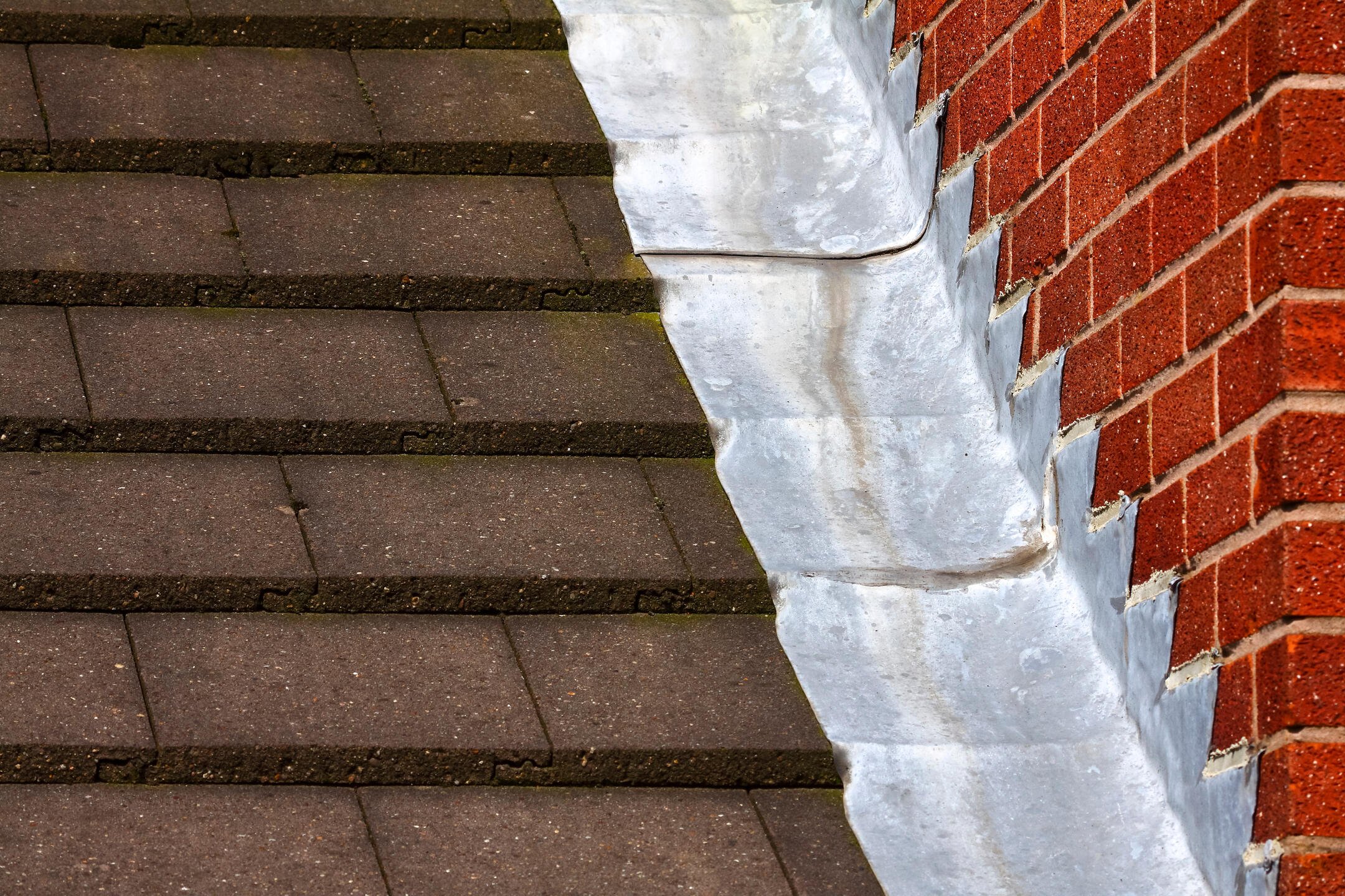 roof flashing types-step flashing between shingles and brick wall