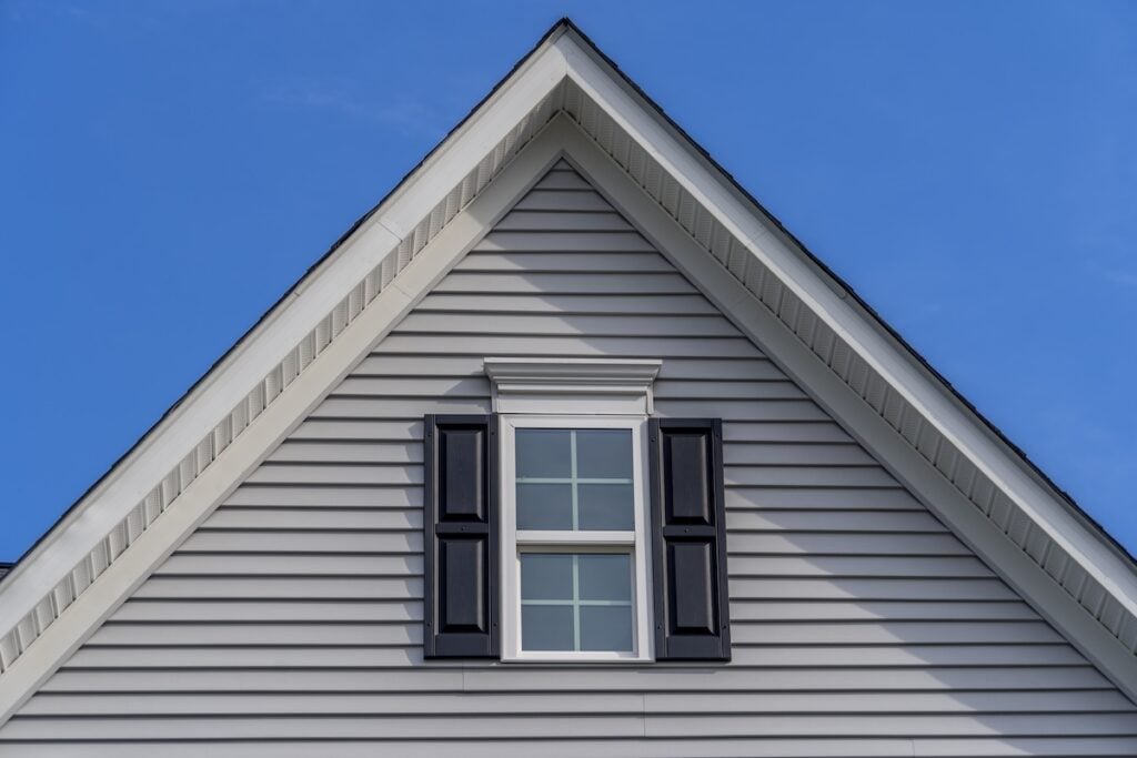Gable roof with window in front of blue sky