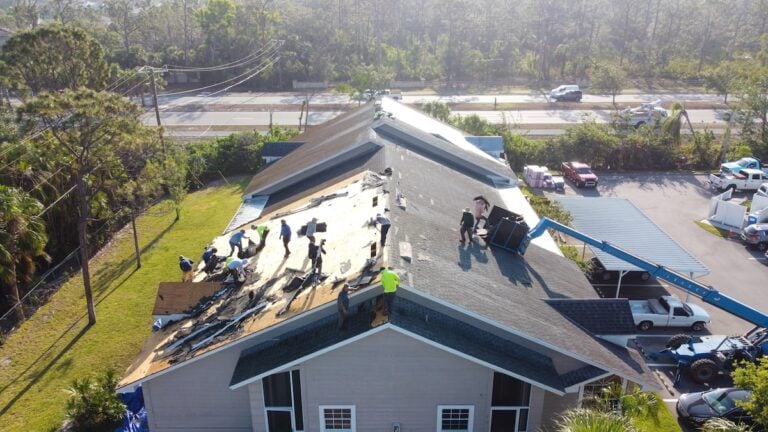Workers repairing a roof damaged by Hurricane Ian in Fort Myers, FL