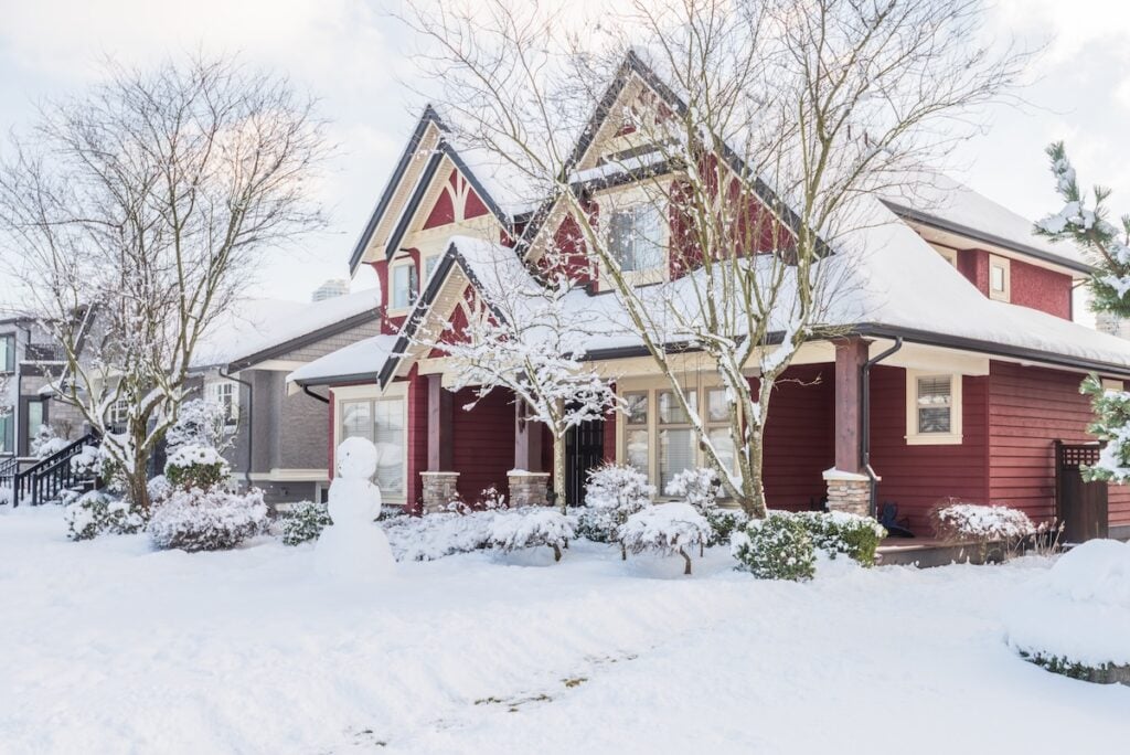 A typical midwestern house in winter. Snow covered. Snowman in front yard